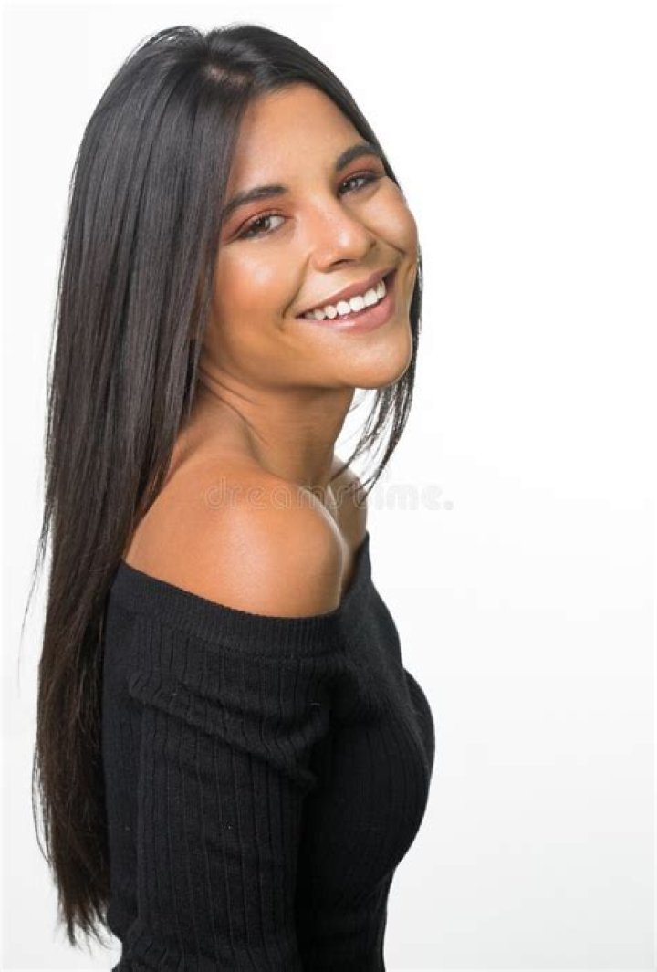 a woman with long dark hair smiling at the camera, wearing a yellow
